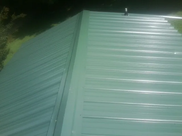 New green metal panels meeting at the ridge of a roof — Flat Roof Repair work by our crew in Glenns Ferry