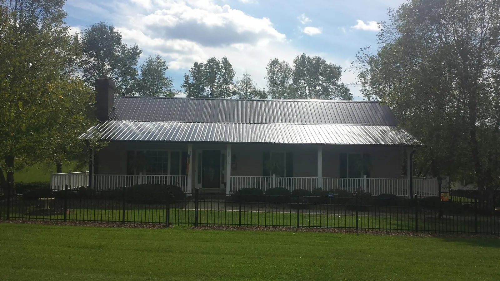 Gray metal roof on a brick ranch with a full width front porch — Gutter Guard Installation work by our crew in Glenns Ferry