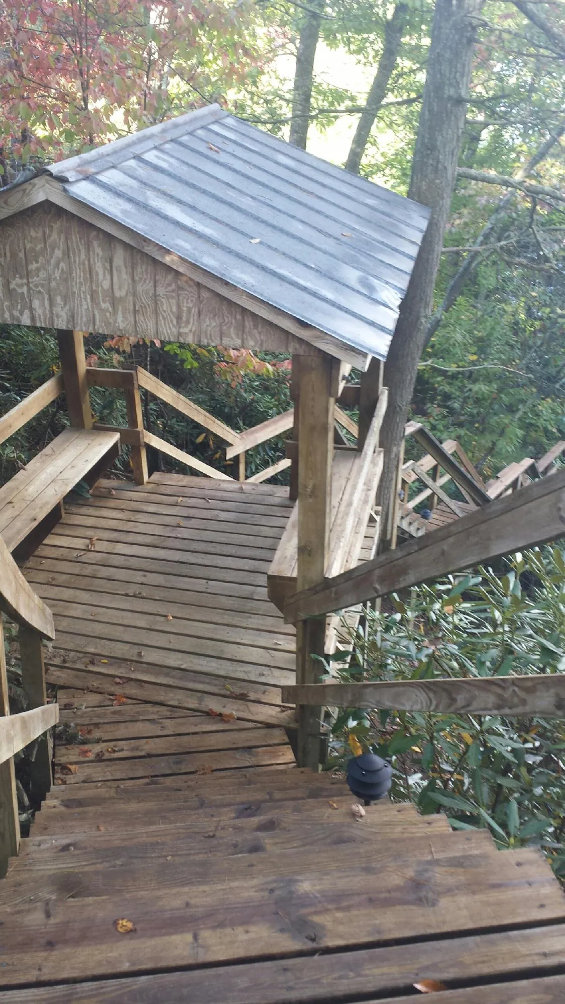 Metal roofed shelter over wooden steps on a wooded walkway — Skylight Repair & Installation work by our crew in Glenns Ferry