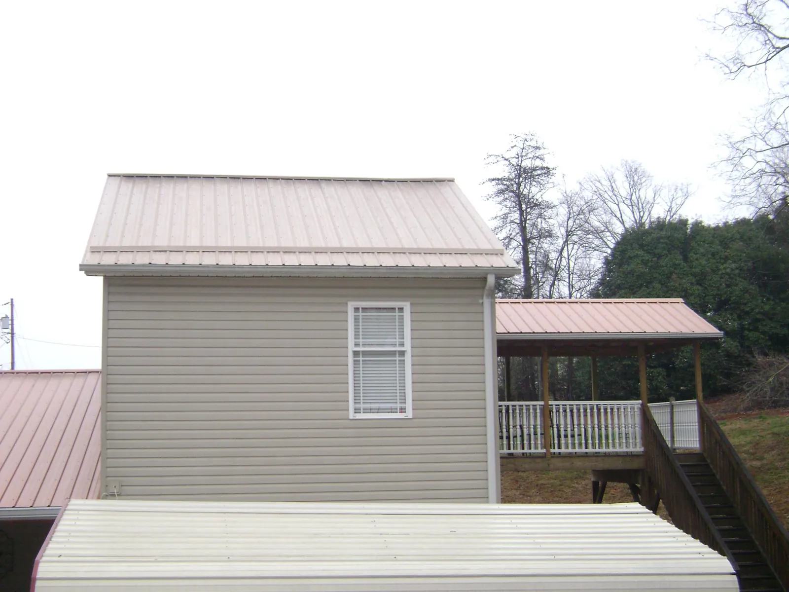 Tan metal roofs on a two story addition and attached porch, from a Roof Replacement job in Glenns Ferry