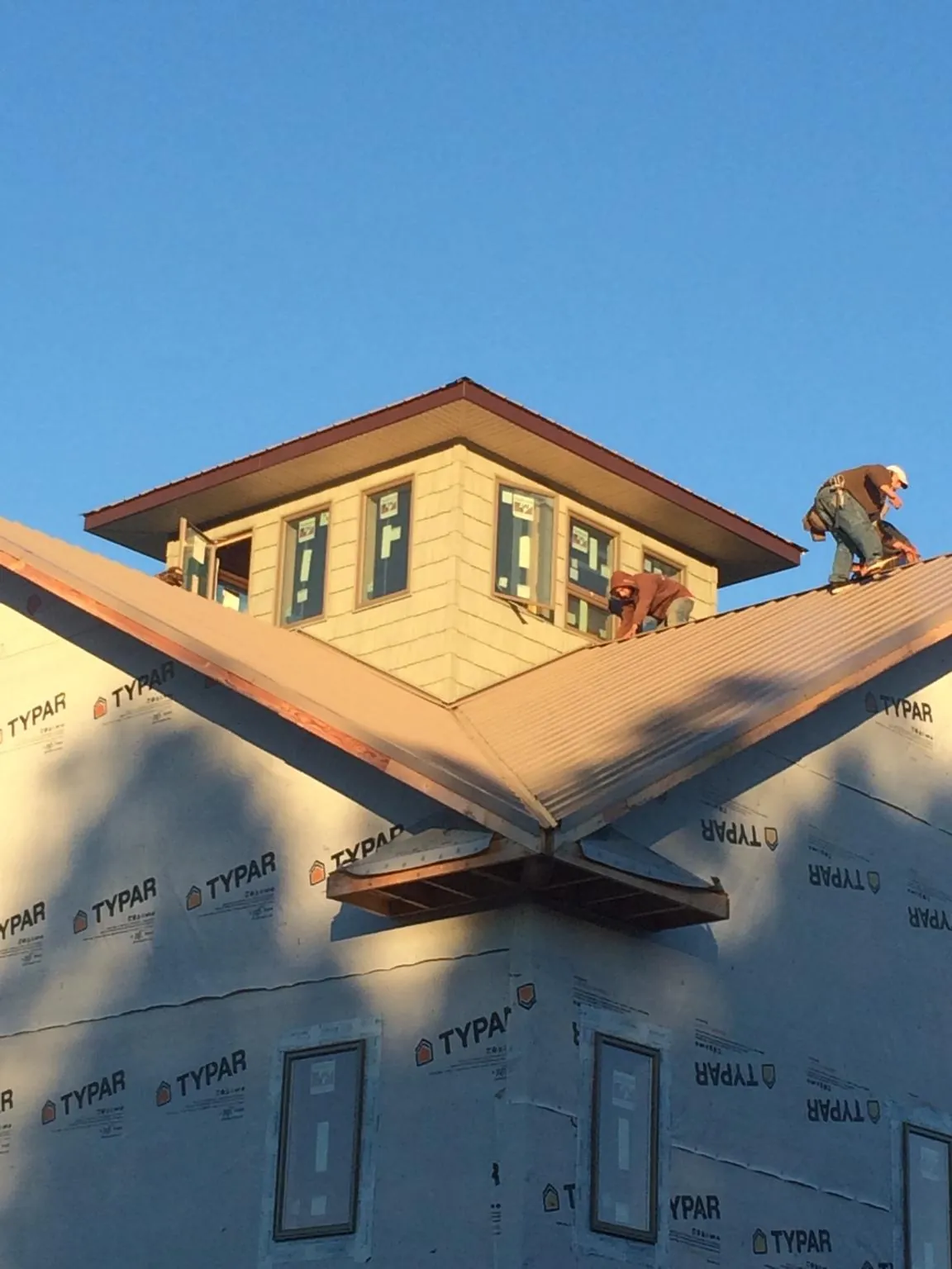 Roofers working around a rooftop cupola on a new metal roof at sunset — Roof Waterproofing in Glenns Ferry by Roofing Brothers